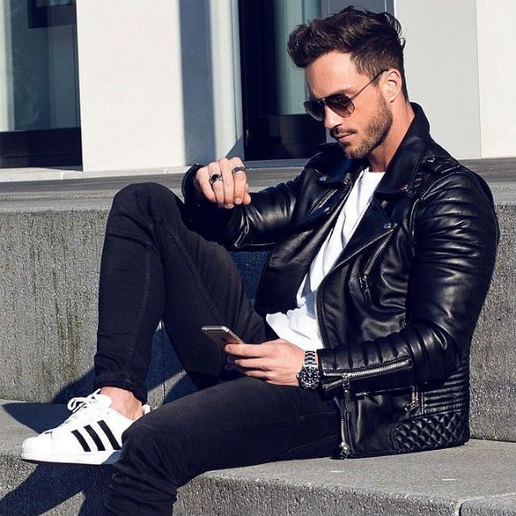 Homem jovem vestindo roupa casual urbana, jaqueta jeans e tênis esportivos